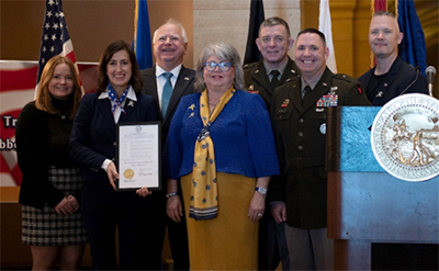 Sydney Richter, MnDOT Commissioner Nancy Daubenberger, Governor Tim Walz, Taylor Kristoffe-Jones, Brig. Gen. Shawn Manke, Brig. Gen. Joe Sharkey, TJ Melcher at a ceremony recognizing MnDOT as a Beyond the Yellow Ribbon organization