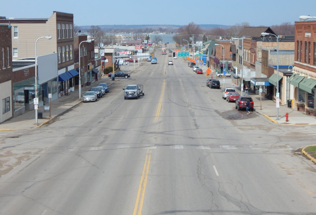 Hwy 28 (Minnesota Ave.) in downtown Glenwood before construction, showing four traffic lanes, two parking lanes, and a faded crosswalk 